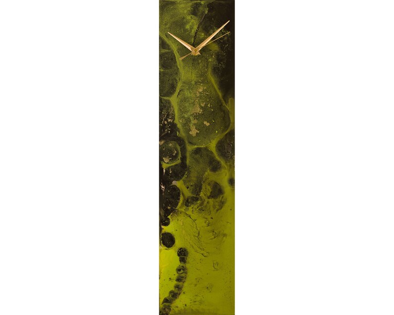 Op de afbeelding: Een verticale klok met een abstract ontwerp in zwart en groen. De wijzerplaat van de klok is wit met gouden wijzers.