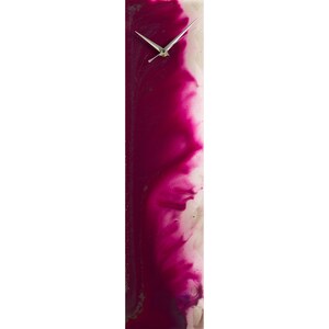 May include: A long, vertical clock with a white face and silver hands. The clock face is partially covered by a pink and white abstract design.