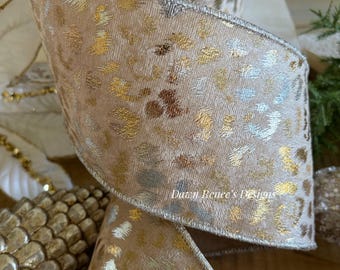 May include: A wide, wired ribbon featuring a beige fabric base with a metallic leopard print pattern in gold and silver tones. The edges are finished with a metallic silver thread. The text Dawn Renee's Designs is printed on the ribbon surface.