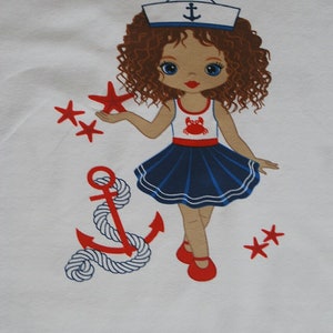 May include: A white t-shirt with a colorful illustration of a girl wearing a sailor hat and a blue and white dress. The girl is holding a red starfish and there is a red anchor with a white rope on the left side of the image. There are also red starfish scattered around the image.