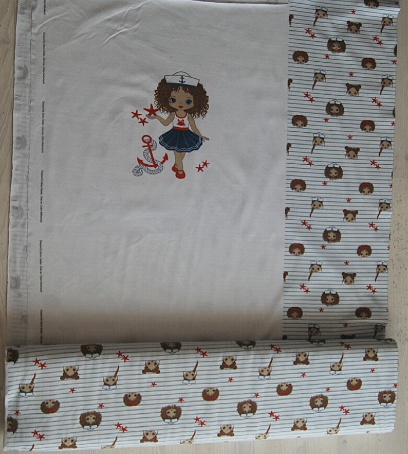 May include: White fabric with a red, white, and blue sailor girl design. The fabric has a repeating pattern of brown and white sailor girls with red stars and anchors.