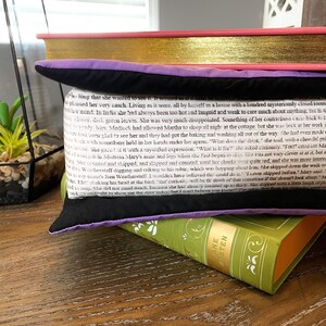 May include: A black and purple throw pillow with a white text overlay on a black background. The text is from a book and reads "so long that she wanted to see it. It seemed as if it innat ὡ&sigmaf; &alpha;&iota;&tau;&epsilon;ί&tau;&alpha;&iota; &sigma;&tau; pleased her very much. Living as it were, all by herself in a house with a hundred mysteriously closed room f her mind. In India she had always been too hot and languid and weak to care much about anything, but in glossy, dark green leaves. She was very much disappointed. Something of her contrariness came back to b berendy. Wirs. Mediock had allowed Martha to sleep all night at the cottage, but she was back at her work uner band been glad to see her and they had got the baking and washing all out of the way. She had even unde we bock with something held in her hands under her apron, "What does the think she said with a cheerful cri Not Delote. She gazed it with a mystified expression, "What is it for?" she asked cariously, "For!" cried our Ma of strength in Mistress Mary's auns and legs when she first began to skap, She was not very clever at at it, but s She counted and skipped, and slipped and counted until her cheeks were quite red, and she was more interes Cow Ben Weatherstaff digging and talking to his robin which was hopping about him. She skipped down the walleto asy-Baane's Ben Weatherstaff. I wouldn't have believed the could do it. I ever skipped before." Mary said te. Eht with a little laugh of aid You wught to show me the door today, but I don't believe you know! The robin hơn b&aacute;c ruinning shaking his head at the bird. that curiosit will be the death of thee sometime if that doesn't look sharp M"