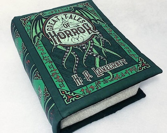 Puede incluir: Un libro de tapa dura verde con una ilustración en blanco y negro de una criatura con tentáculos en la portada. El título del libro es "Great Tales of Horror" de H.P. Lovecraft.