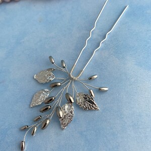 May include: Silver hair comb with a delicate design of leaves and beads. The comb has two prongs for easy insertion into hair.
