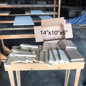 May include: A cardboard box labeled "14"x10"x6" with a variety of wooden boards and planks inside. The box is sitting on a wooden table.