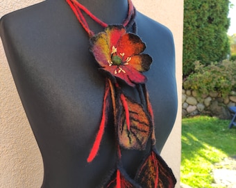 May include: A long, red and black felt necklace with a large, orange, yellow, and red felt flower and three felt leaves.