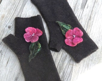 Può includere: Un paio di guanti senza dita neri con fiori di feltro rosa e foglie di feltro verde.