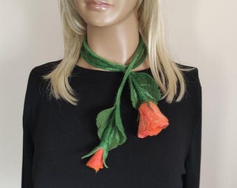 May include: A felted scarf featuring a green stem and leaves with two orange rose buds. The scarf is draped around a mannequin's neck, showcasing the floral design and color contrast against a black top.