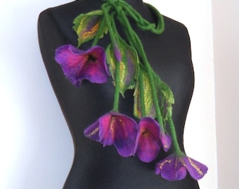 May include: A purple and green felt flower necklace. The flowers are made of felt and have a textured look. The necklace is long and can be worn as a statement piece.