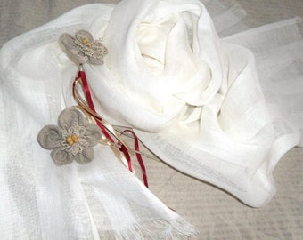 May include: A white linen scarf with two beige fabric flowers and a red ribbon.
