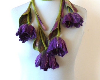 May include: A purple felt flower necklace with green felt leaves. The necklace is made of felt and is a unique and beautiful piece of jewelry.