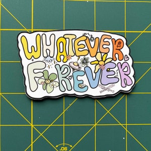 Puede incluir: Una pegatina con el texto "Whatever Forever" en colores arco&iacute;ris con una variedad de peque&ntilde;as ilustraciones que incluyen flores, estrellas y un platillo volante.
