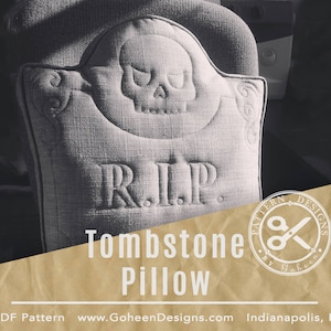 Puede incluir: Una almohada gris en forma de lápida con una calavera y las palabras "RIP" bordadas en ella. La almohada está sobre una superficie marrón. El texto "Tombstone Pillow" está escrito debajo de la almohada.