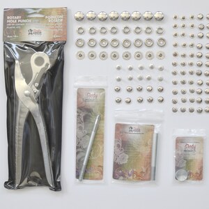 Pu&ograve; includere: Un set di bottoni a pressione in metallo argentato con un punzone rotativo, uno strumento di fissaggio e un martello. La confezione include il testo "Rotary Hole Punch" e "Poincon Rotatif".