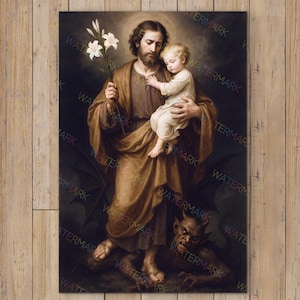 Può includere: Un dipinto religioso incorniciato raffigura un uomo in abito marrone che tiene in braccio un bambino e dei gigli bianchi. Il dipinto è ambientato su uno sfondo scuro con figure in basso. L'opera d'arte è esposta su una parete di legno sopra una poltrona bianca e un tavolino in legno.