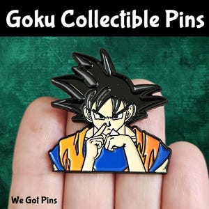 May include: A metal enamel pin featuring the character Goku with spiky black hair, wearing an orange and blue gi, performing a finger-to-nose gesture. The pin includes black outlines and vibrant colours, with the text Goku Collectible Pins above.