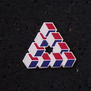 May include: A silver pin with a red, white, and blue geometric design. The design is a triangle made up of stacked cubes.