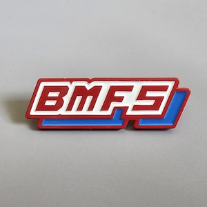 May include: A rectangular badge featuring the letters "BMFS" in white, with a red outline and blue base. The design suggests a logo or emblem.