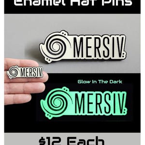 May include: Two enamel hat pins with the word "MERSIV" in black lettering. One pin is white with a black spiral design, and the other glows green in the dark. The text "Limited Edition Collectible Enamel Hat Pins" is at the top.