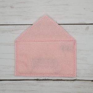 May include: A pink felt envelope with a white stitched border.