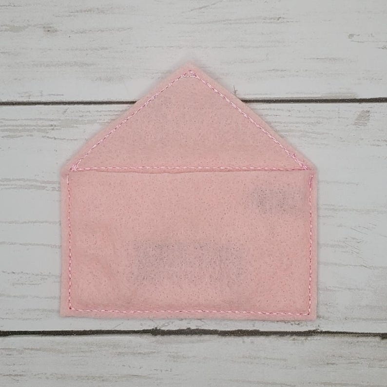May include: A pink felt envelope with a white stitched border.