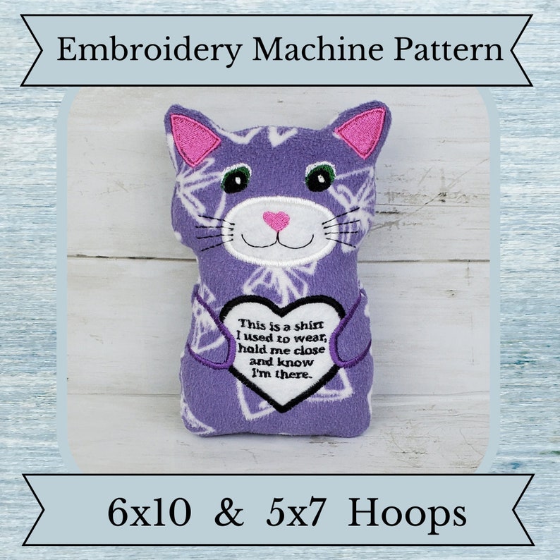 May include: A purple cat-shaped plush toy with pink ears and a pink heart-shaped nose. The toy has a white geometric pattern and a heart-shaped patch with text. The text reads: "This is a shirt I used to wear, hold me close and know I'm there."