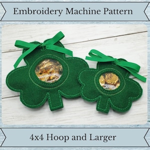 May include: Two green felt shamrock-shaped treat bags with clear plastic windows. The bags are decorated with green ribbon bows and are suitable for a 4x4 hoop embroidery machine.
