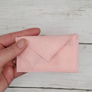 May include: A pink felt envelope with a white stitch detail.