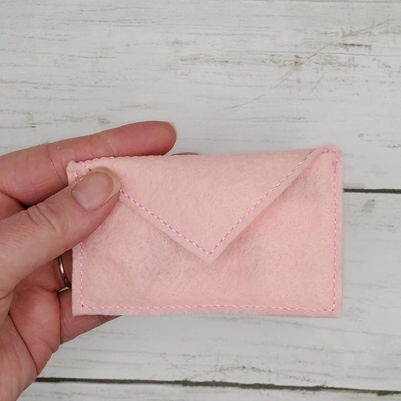May include: A pink felt envelope with a white stitch detail.