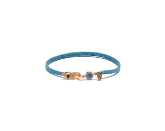 May include: A light blue bracelet with a gold clasp and an evil eye charm. The bracelet is made of a woven material and features a small gold charm. The evil eye charm has a blue center and gold accents.