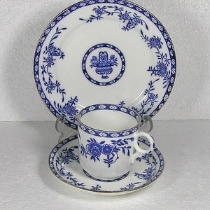 Puede incluir: Un juego de taza y platillo de porcelana azul y blanca con un diseño floral. La taza y el platillo tienen un borde dorado.