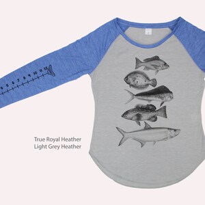 May include: A light grey heather and true royal heather long-sleeved t-shirt with a fish ruler on one sleeve and a graphic of five different fish on the front. The text "True Royal Heather Light Grey Heather" is printed below the graphic.