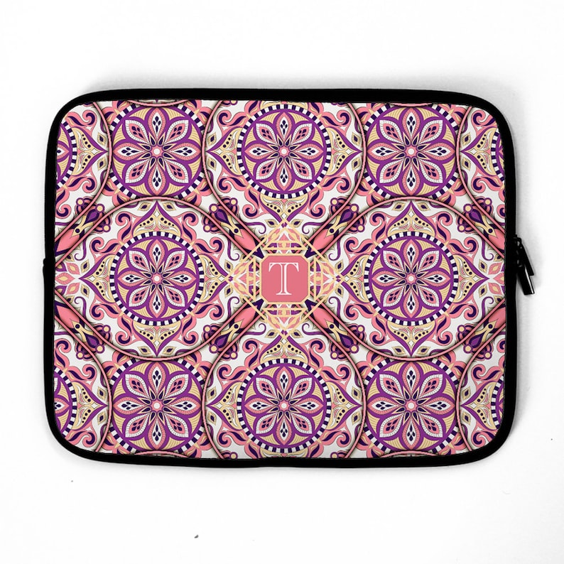 May include: A laptop sleeve with a pink, purple, and gold mandala pattern. The letter "T" is in the center of the design.