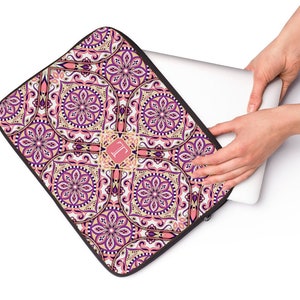 May include: A pink, purple, and gold laptop sleeve with a mandala pattern and a monogrammed initial "L" in the center.