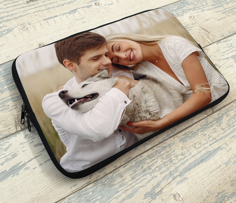 May include: A couple and their dog are hugging in a field. The couple is wearing white shirts and the dog is white and gray.