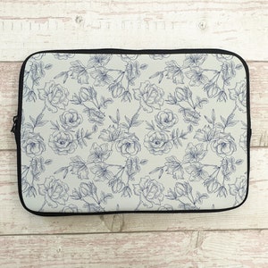 May include: A white laptop sleeve with a blue floral pattern. The pattern features delicate line drawings of roses and leaves.