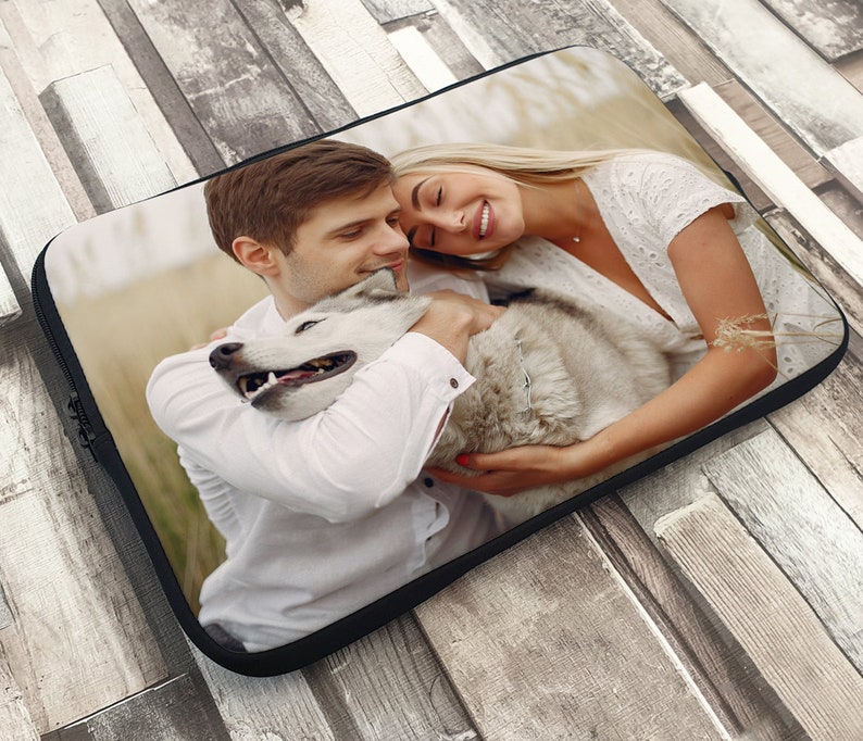 May include: A couple and their dog are hugging in a field. The man is wearing a white shirt and the woman is wearing a white dress. The dog is a white husky.