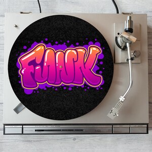 May include: A black turntable mat with a purple, pink and orange graffiti design that says "Flack".