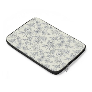 May include: A laptop sleeve with a cream background and a blue floral pattern. The sleeve has a zipper closure.