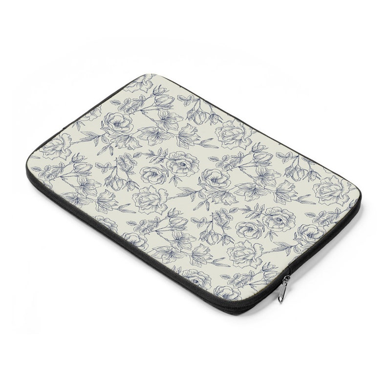 May include: A laptop sleeve with a cream background and a blue floral pattern. The sleeve has a zipper closure.