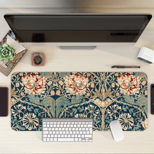 Peut inclure: Un tapis de bureau à motif floral bleu et or avec un clavier et une souris blancs dessus.