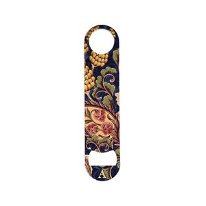 May include: A blue and gold bottle opener with a floral design and the letter "A" on the bottom.