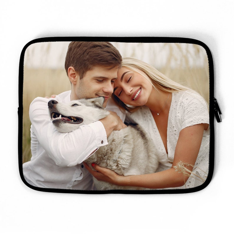 May include: A couple is sitting in a field with their dog. The couple is hugging and the dog is looking up at them. The couple is wearing white shirts and the dog is a husky.