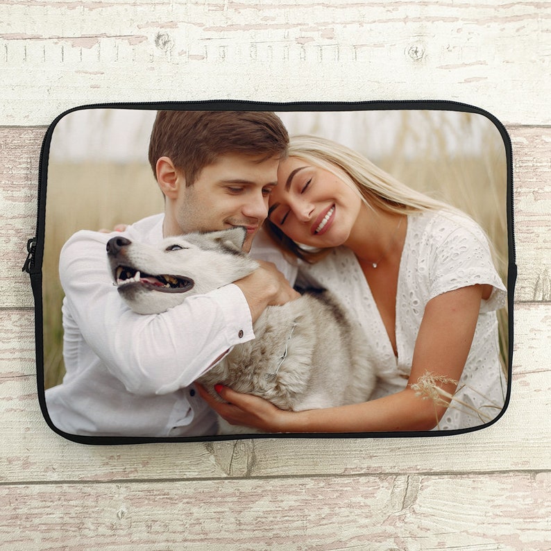 May include: A couple and their dog are cuddling in a field of tall grass. The couple is wearing white shirts and the dog is white and gray.