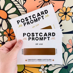 Puede incluir: Dos postales rectangulares blancas con el texto POSTCARD PROMPT en negro, que presentan un panel dorado para rascar en el centro. La tarjeta superior está marcada como AUG 2026 y la inferior como SEP 2026, con el texto CREATIVITY UNDER CAPITALISM abajo.