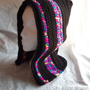 May include: A black crocheted hood with colourful trim. The hood has a ribbed texture and is decorated with bright pink, blue, yellow, and green yarn. The hood is designed to be worn over the head and shoulders.