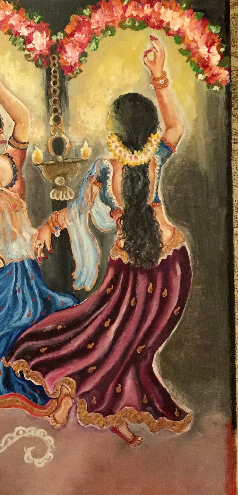 May include: A painting of two women in traditional Indian clothing dancing under a floral garland. The woman in the foreground is wearing a burgundy skirt with gold accents and a blue top. The woman in the background is wearing a blue skirt with gold accents and a white top.