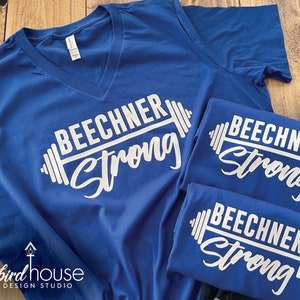 May include: Three royal blue t-shirts with a white graphic design. The design features the word "Beechner" with a barbell and the word "Strong" underneath.