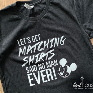May include: A dark gray t-shirt with white text that reads "Let's get matching shirts said no man ever!" and a white Mickey Mouse silhouette.