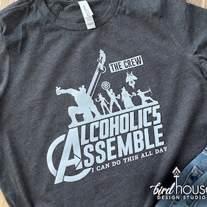 May include: A dark gray t-shirt with a white graphic of the Avengers characters. The text on the shirt reads "The Crew Alcoholics Assemble I Can Do This All Day".